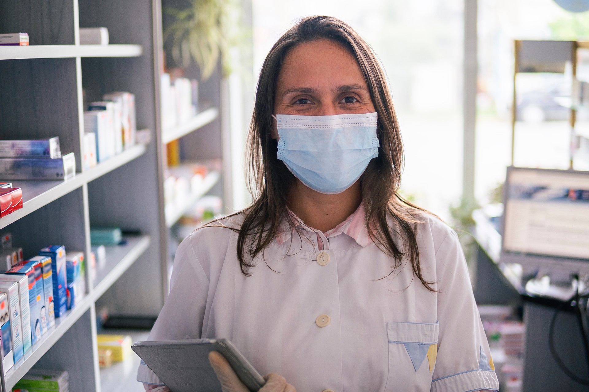 Portrait of an hispanic pharmacist's working day during COVID-19 pandemic. Using technology.