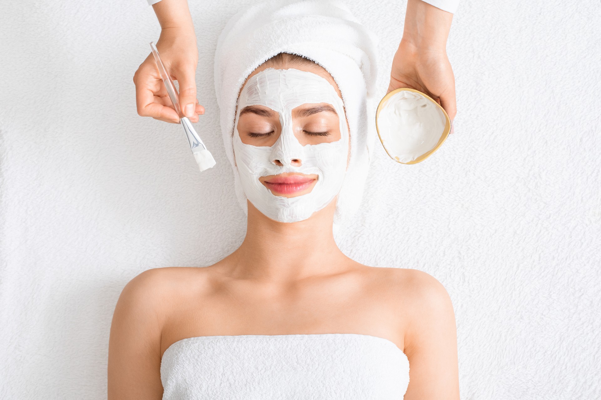 Spa therapist putting facial mask for young lady